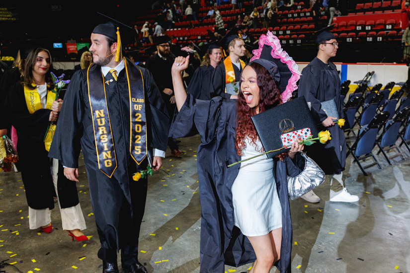 (Hi Res) SUNY Broome GRADUATION 2025 432 Web Two excited graduates walking down the aisle during the 2025 Commencement ceremony.