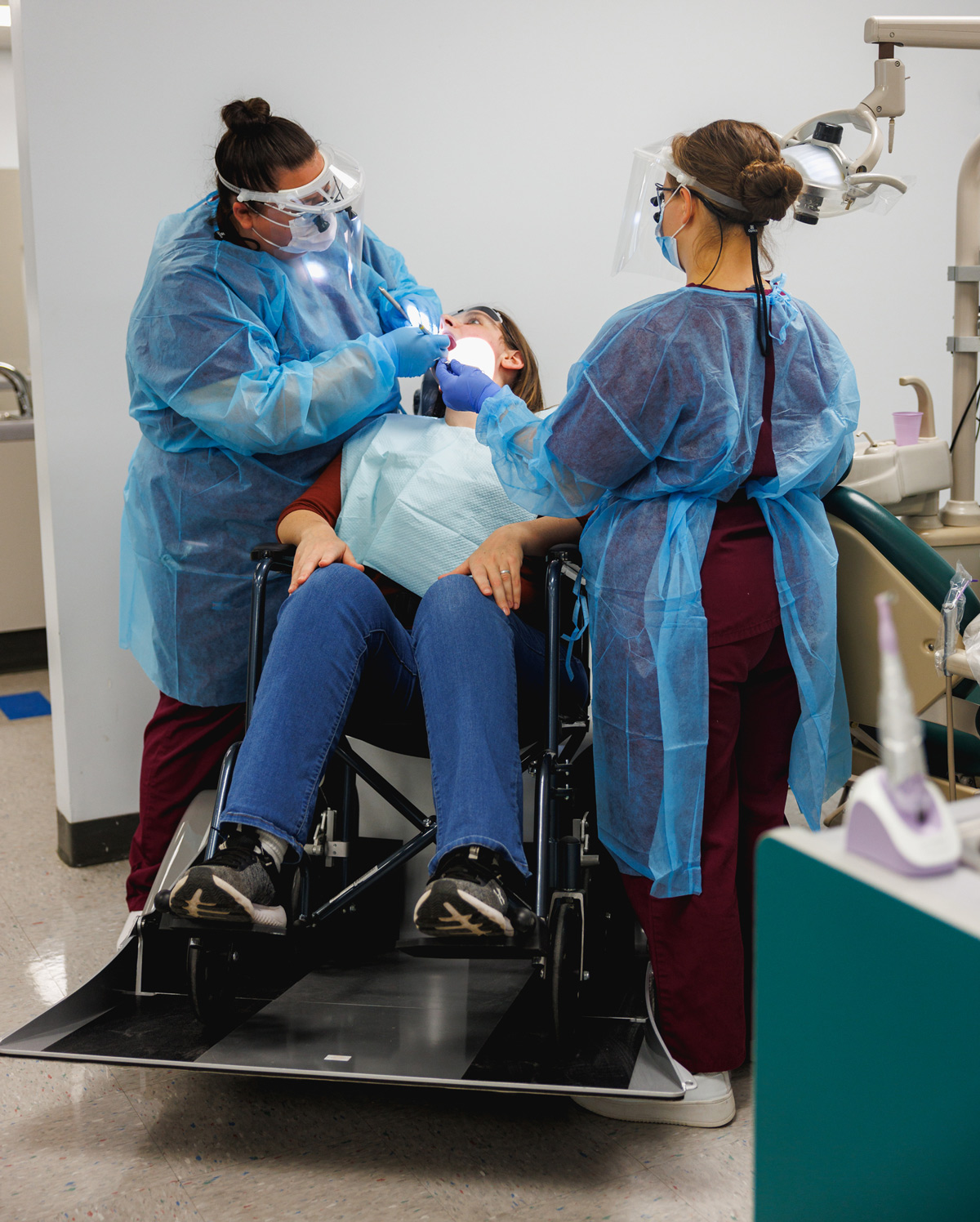 SUNY Broome students clean the teeth of a patient using the wheelchair adaptable recliner.