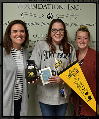 Rae smiles with Lisa and Jamie as she is presented with her VIP items.