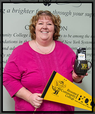 Angela grins and holds up a BCC banner