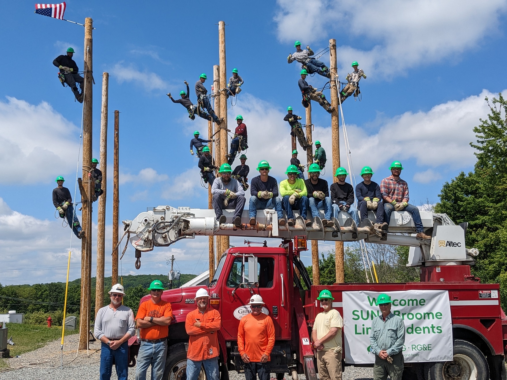 Lineworker Training class posing on poles and in front of the truck.