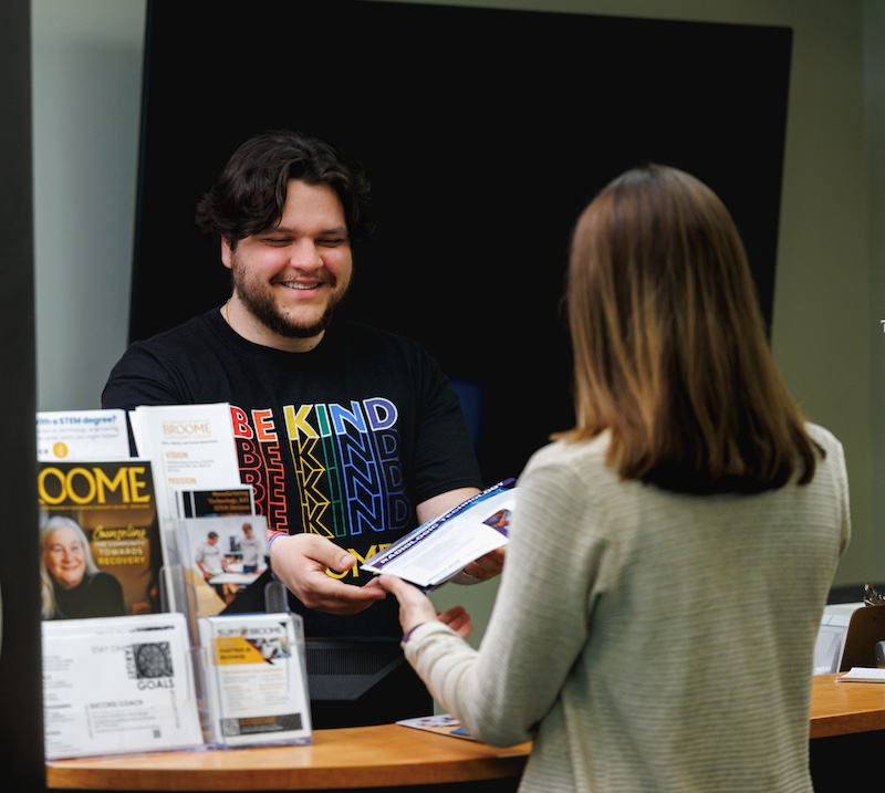 (Hi-res)-ADMISSIONS-Walk-in-Wednesday-Promos-6 Teacher helping a student with his classwork in a library.