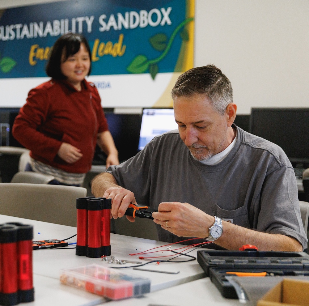 Adult Learner Teacher helping a student with his classwork in a library.
