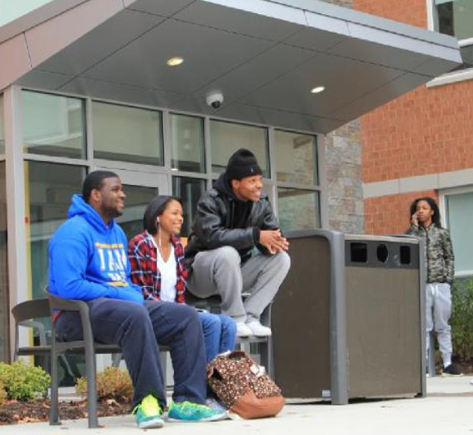 3 Students on a bench just outside the Student Village main entrance